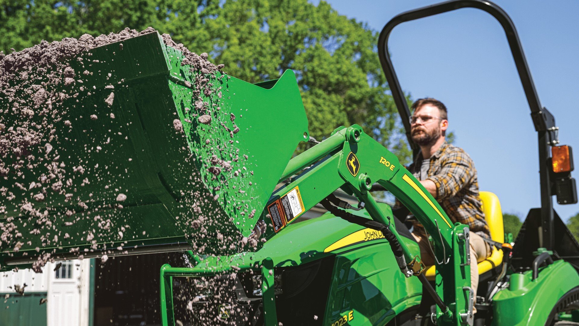 1023E Compact Utility Tractor moving dirt in loader bucket