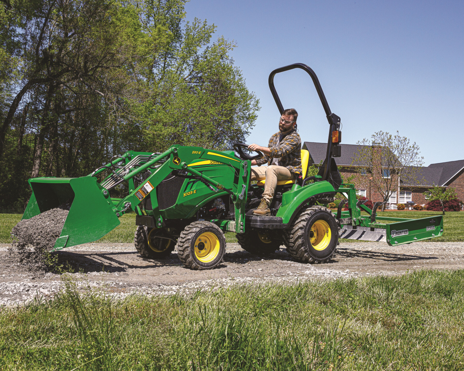 John Deere 1023E tractor operator grating gravel on their property.