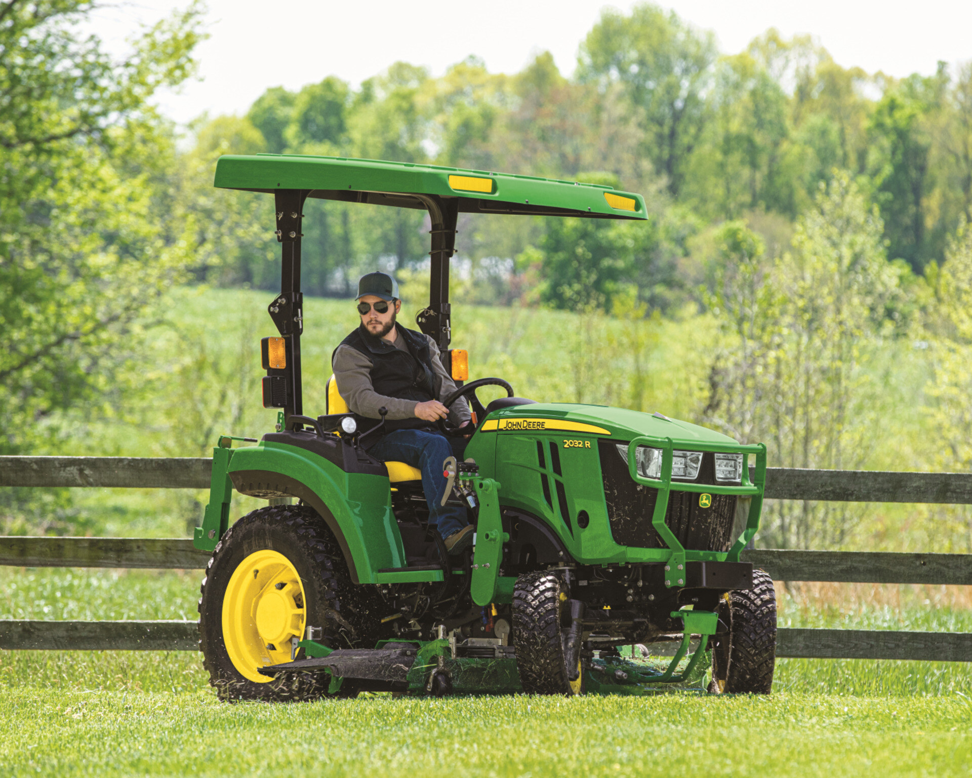 John Deere 2032R operator mowing a field.