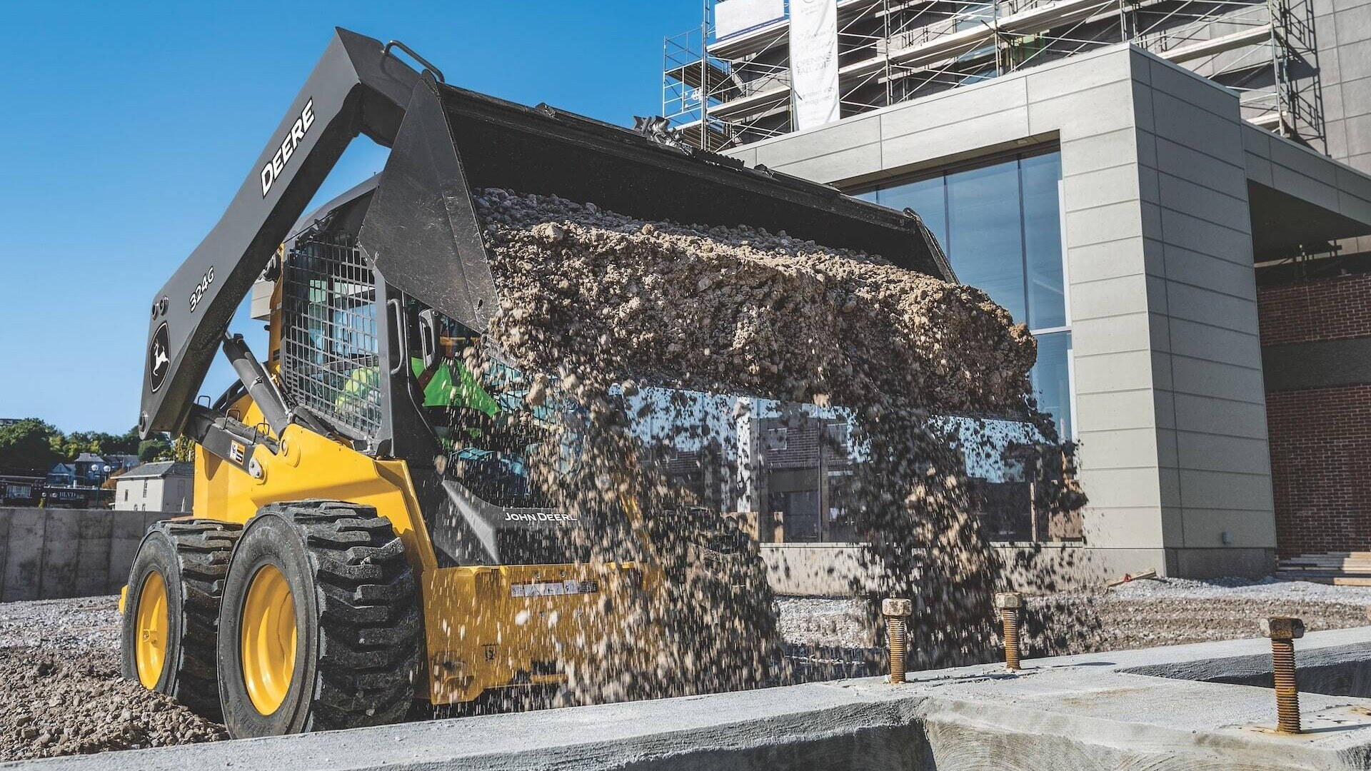 324G Skid Steer dumping gravel on a construction site