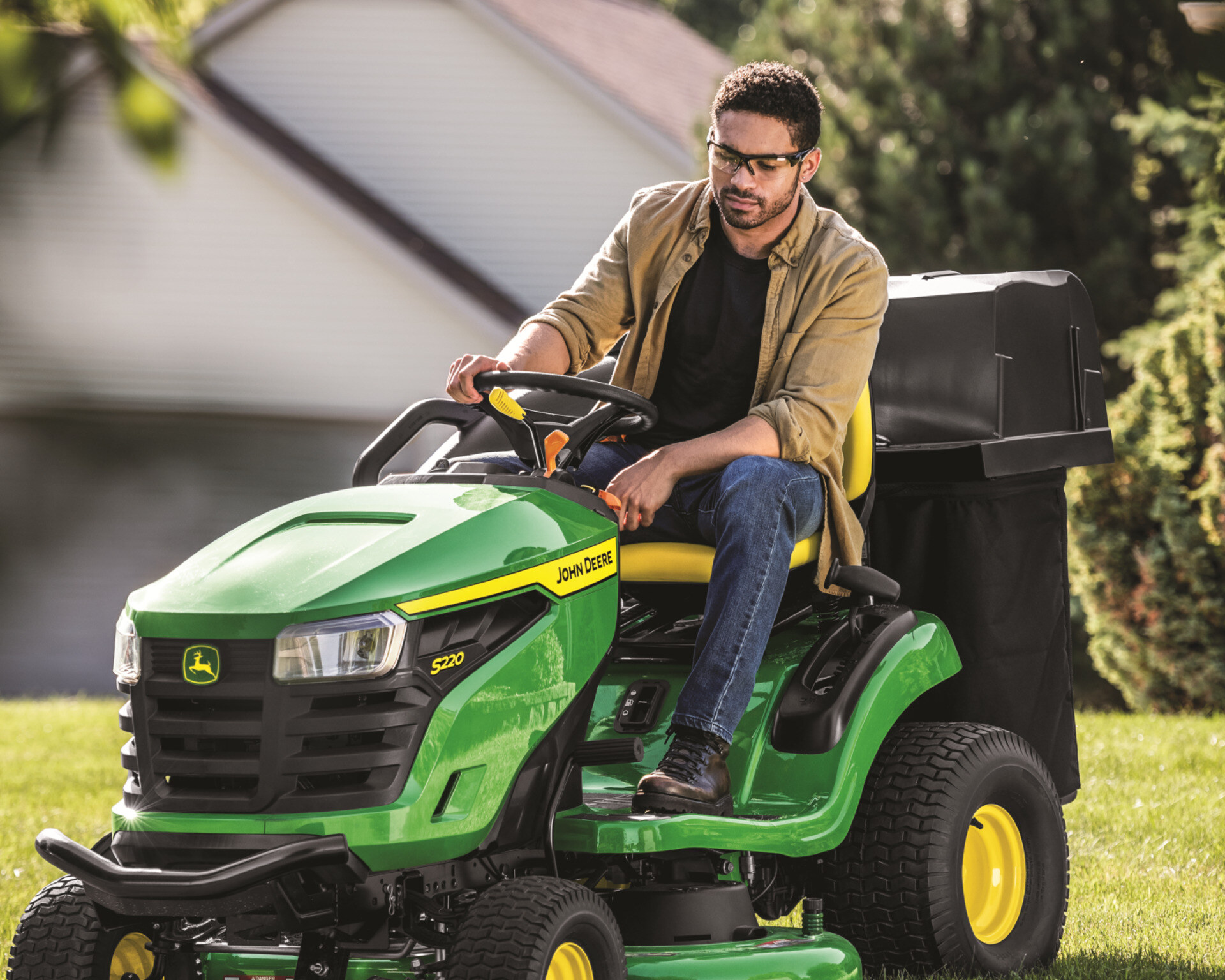 A man mows a lawn with a John Deere lawn tractor.