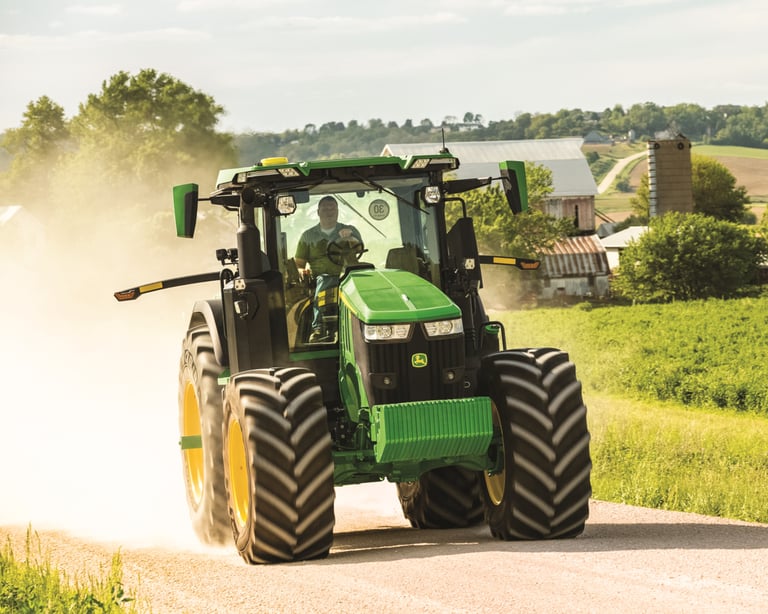 A farmer operates a John Deere 7R