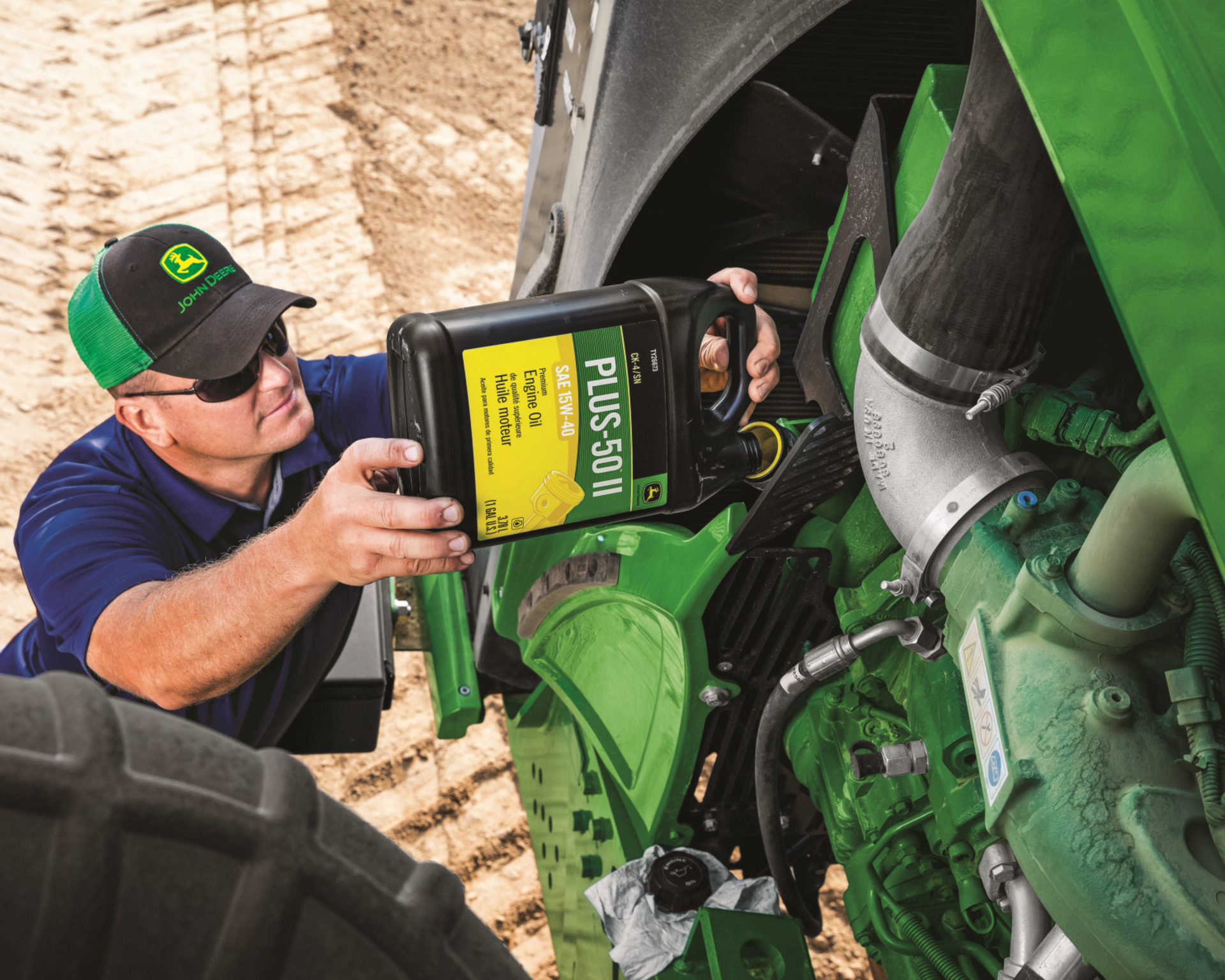 A John Deere technician replaces oil in a machine.