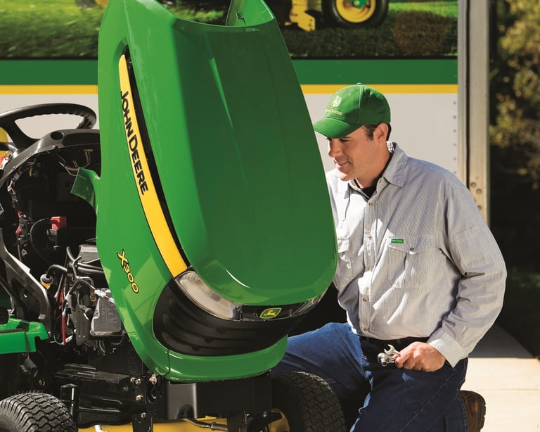 A service technician checks a John Deere X300 mower.