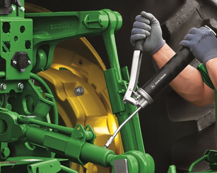 A service technician works on John Deere tractor.