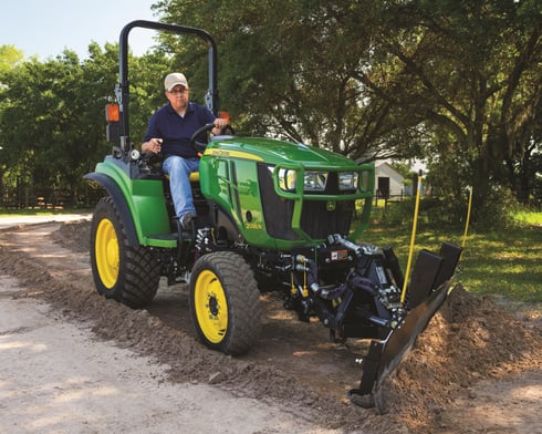 A man operates a tractor built with a John Deere tractor package.