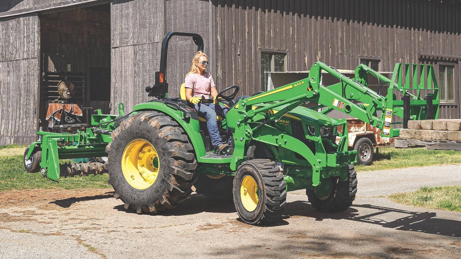 4066M Compact Utility Tractor on a farm lifting material