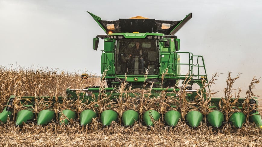 john deere combine harvesting corn in a field