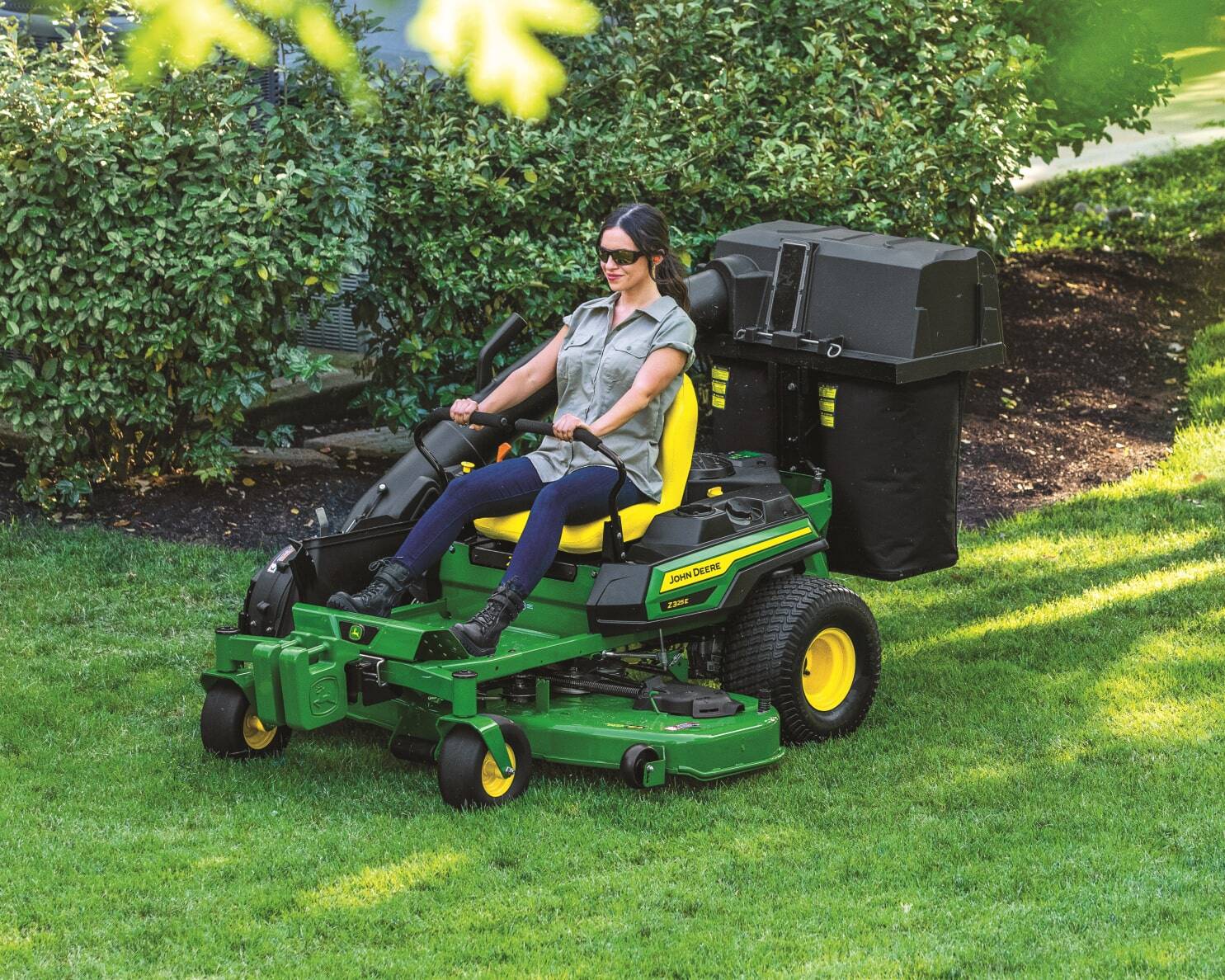 Z325E ZTrakT Mower, 54-in. deck being driven by a women picking up leaves