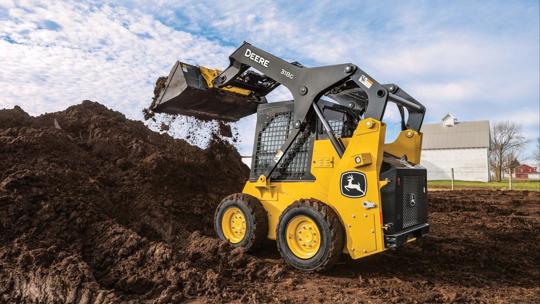 Skid steer 318G moving dirt on a farm