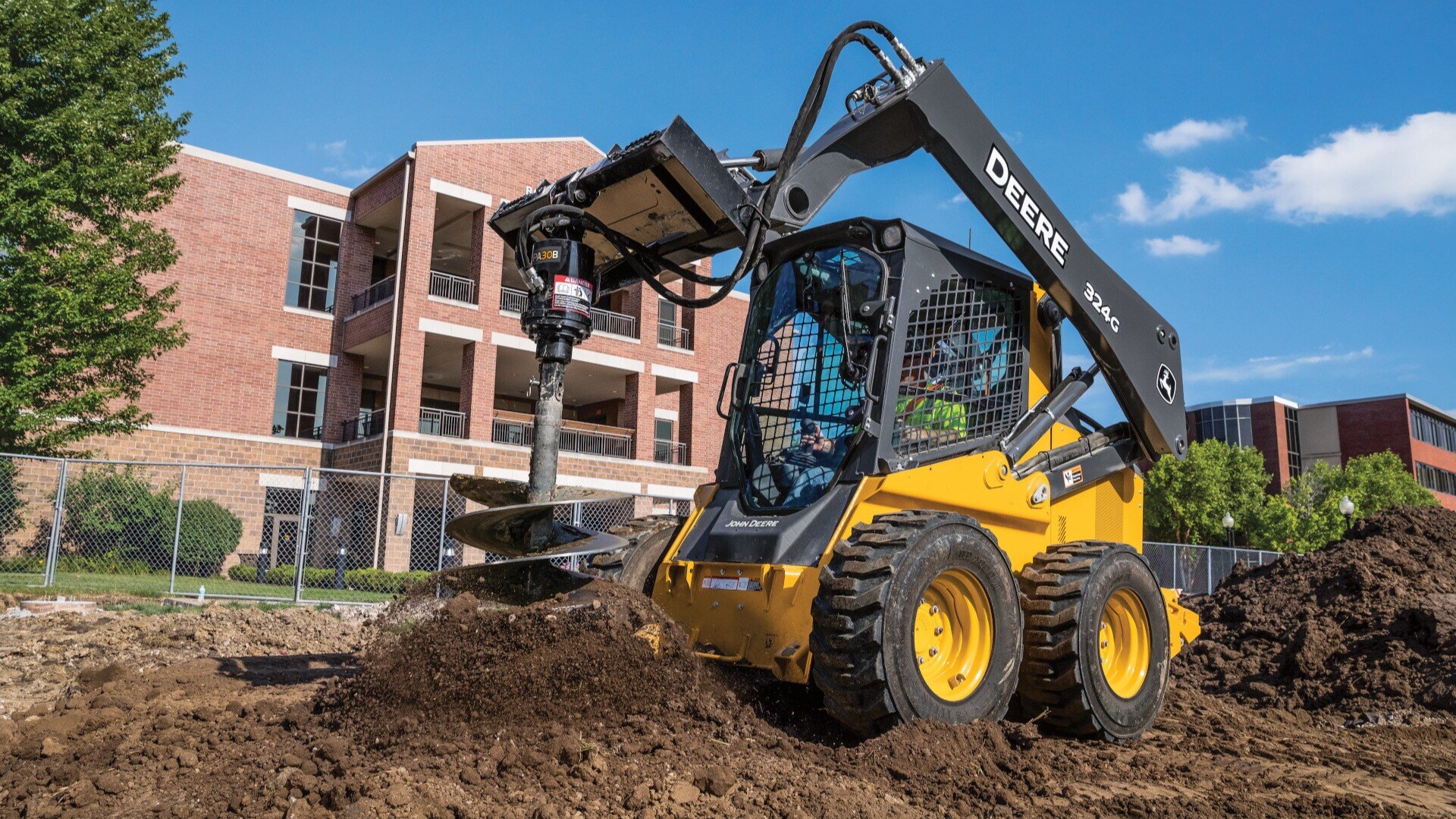 JD Skid Steer drilling a hole using a specialize attchement