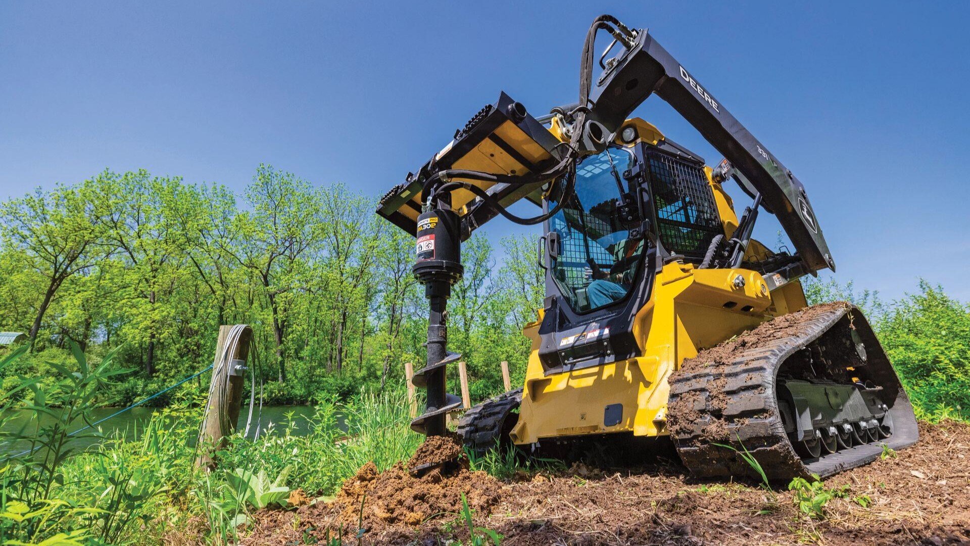 Track Loader with Auger Attachment digging Post Hole