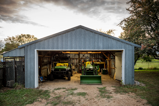 Compact utility Tractor parked next to a john deere gator in a barn